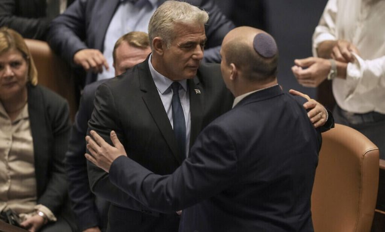 رئيس الوزراء نفتالي بينيت، من اليمين، وخليفته المؤقت يئير لبيد يتحدثان بعد تمرير مشروع قانون لحل الكنيست، 30 يونيو، 2022 (AP Photo / Ariel Schalit)