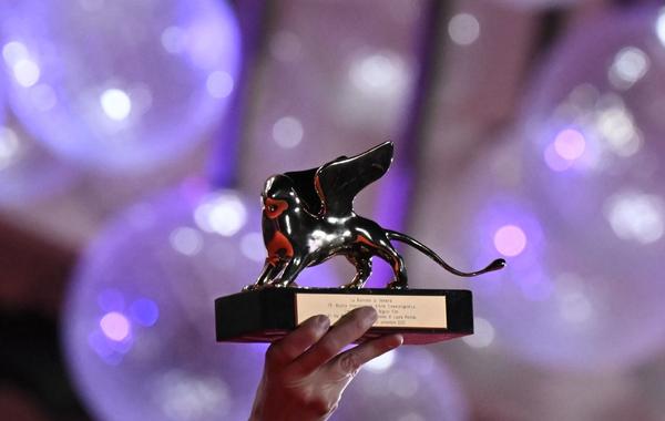 جائزة الأسد الذهبي تحملها المخرجة الأمريكية لورا بويتراس (US director Laura Poitras holds the Golden Lion for Best Film). مصدر الصورة:  Tiziana FABI / AFP
